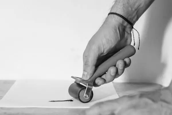 Una mano pasando un rodillo sobre una superficie clara